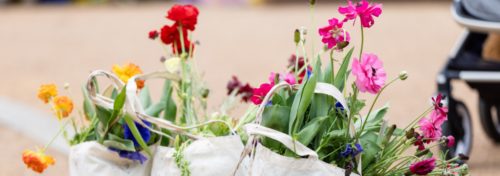 Linen bags of flowers with their stems sitting on the ground.