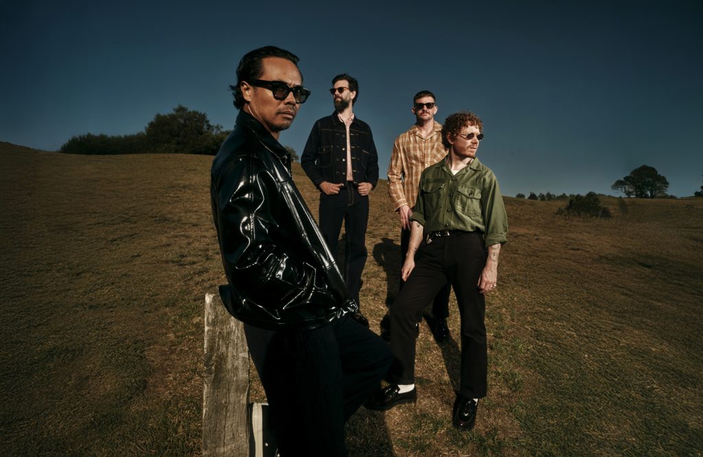 A four-piece band poses outside in a paddock