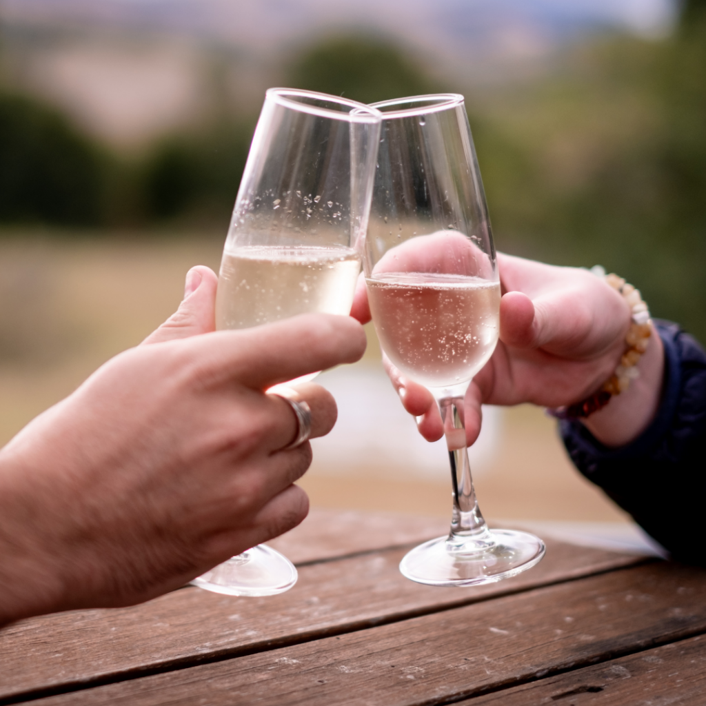 two hands holding sparkling wine glasses together