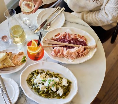 Shared plates and drinks are served on a restaurant table, viewed from above during a dining experience