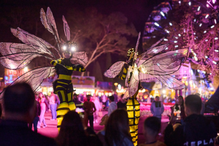 Visitors explore illuminated pathways and glowing floral displays beneath decorative light installations at night.