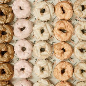 Display of Cannoli Brother's assorted glazed doughnuts in multiple flavours, arranged in neat rows.